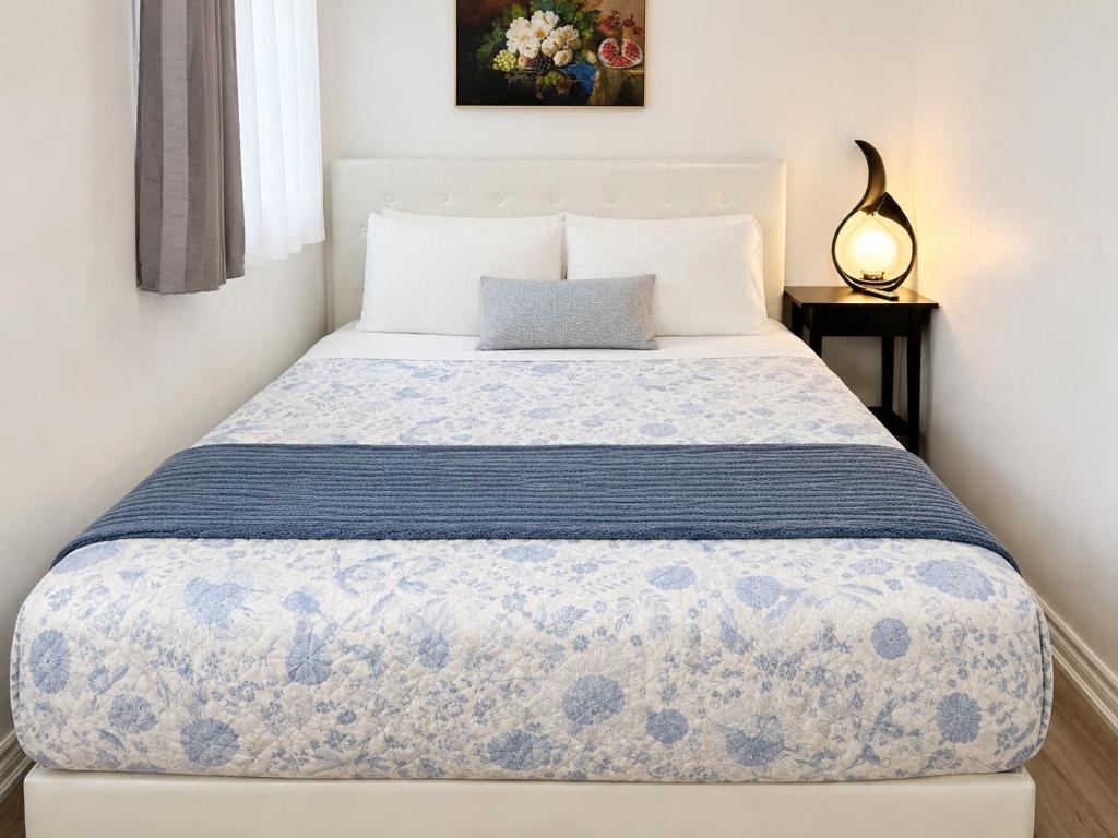 ein Schlafzimmer mit einem Bett mit einer blau-weißen Tagesdecke in der Unterkunft TononHouse in Toronto