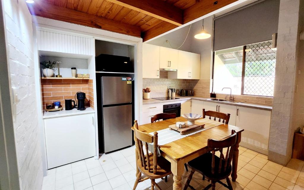 a kitchen with a wooden table and a refrigerator at Poolside Retreat 250m From Beach Resort Facilities in Mandurah