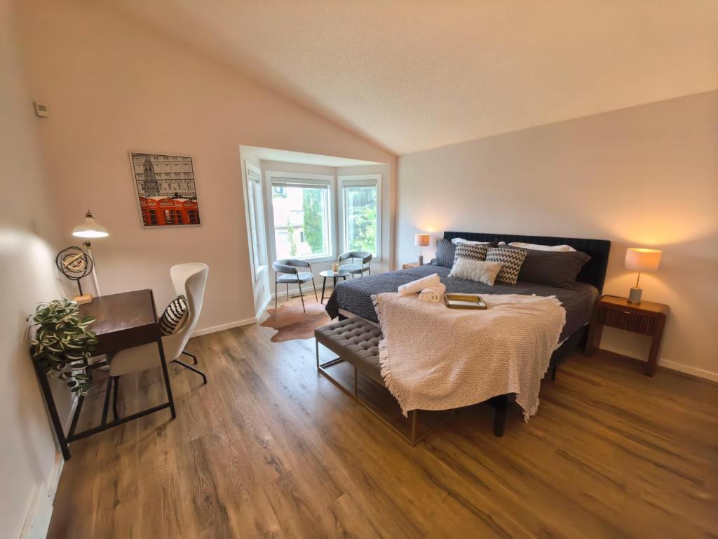 a bedroom with a bed and a table and a desk at Metta Stays Edgemont in Calgary