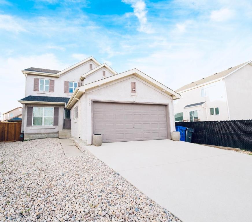 a white house with a garage in a driveway at Cozy Prairie Mansion in Winnipeg