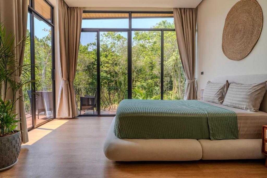 a bedroom with a bed and a large window at ArtiZen Hideout near Hin Kong Beach in Hinkong