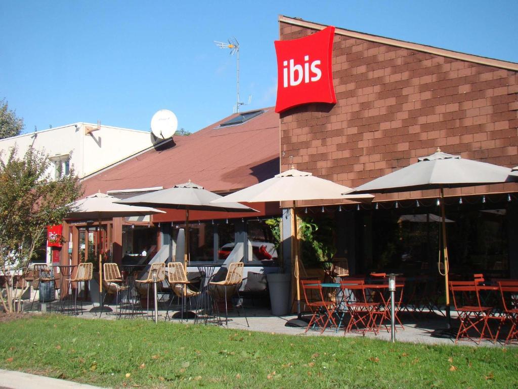a restaurant with tables and chairs and a red sign at ibis Bourg en Bresse in Bourg-en-Bresse