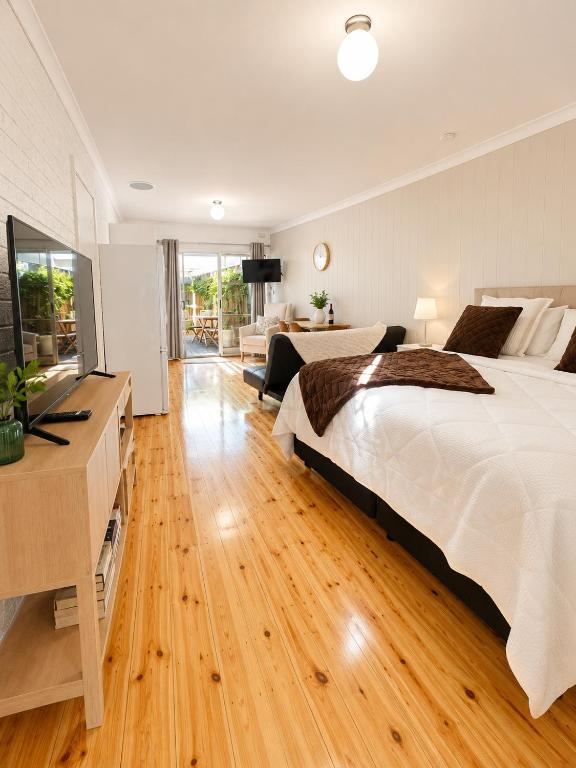 a bedroom with a large white bed and a television at Verandah Suite in Seacliff