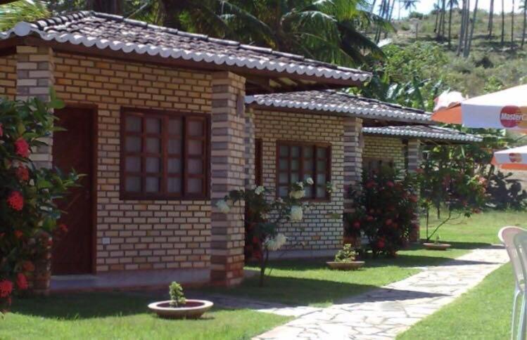 a small brick house in a yard at Pousada Chalés do Cunhaú in Canguaretama