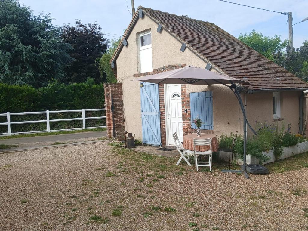 a small house with a table and an umbrella at Le petit nid de Muzy in Muzy