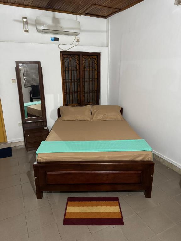 a bed sitting in a room with a mirror at Honey guest Batticaloa in Batticaloa