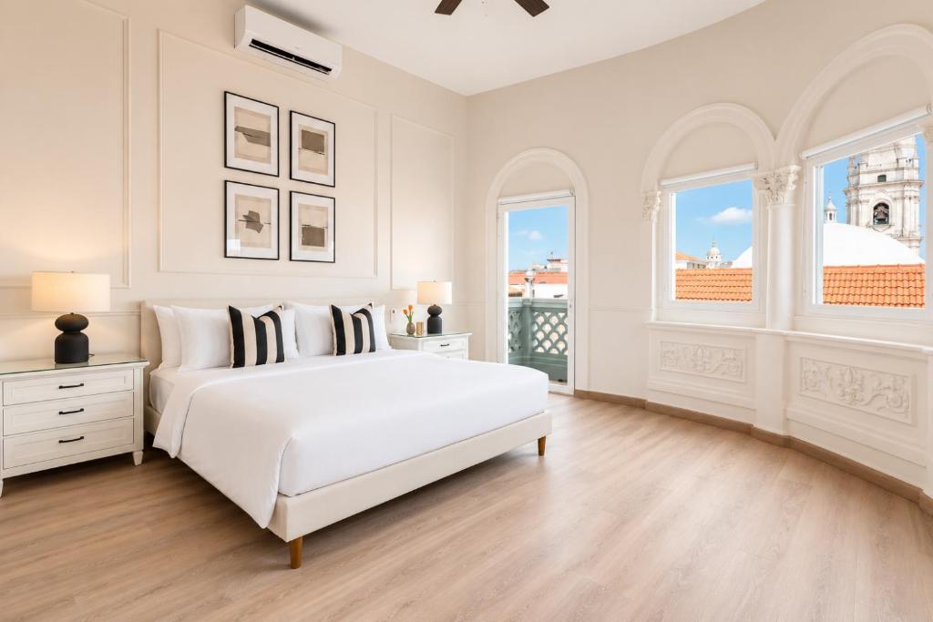 a white bedroom with a large white bed and windows at Hotel Magnolia Boutique in Panama City