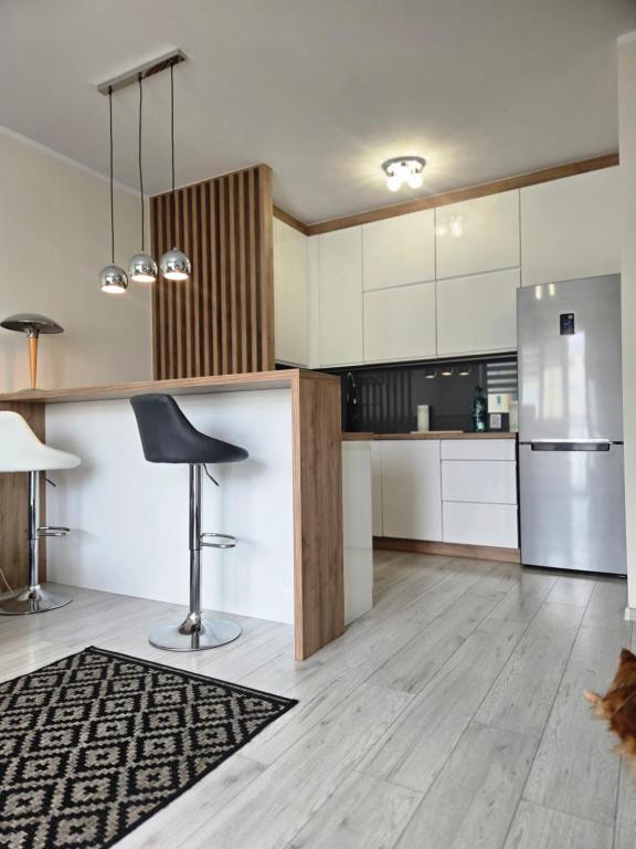 a kitchen with white cabinets and a black stool at Apartament Okulickiego 80 in Gorzów Wielkopolski