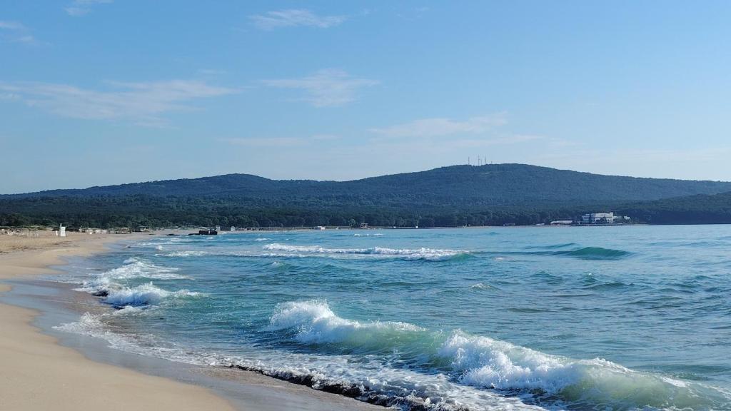 a beach with some waves in the ocean at Апартамент 310 in Primorsko