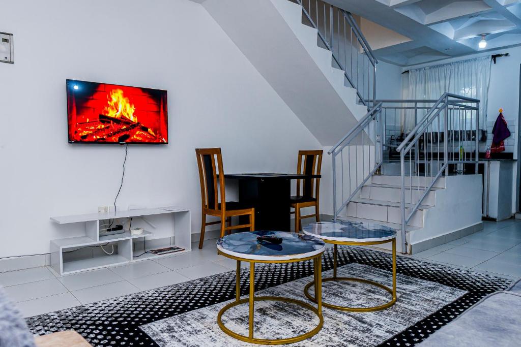 a living room with two tables and a tv on the wall at Serena Road Villa C in Mombasa