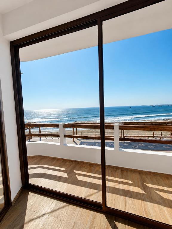 a room with a view of the beach through a window at Family Surf Chicama in Puerto Chicama