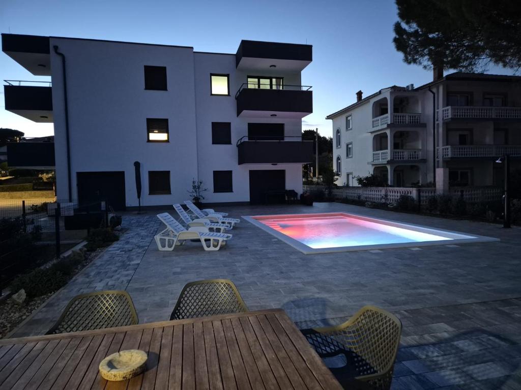 a swimming pool with chairs and a table and a building at Natalija City 2 in Krk