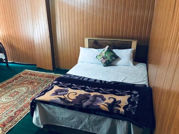 a bedroom with a bed with a wooden wall at Rama lake view Hotel in Astor