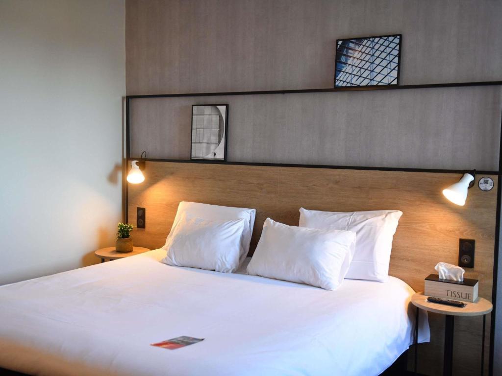 a bedroom with a large bed with white pillows at ibis Chateauroux in Châteauroux