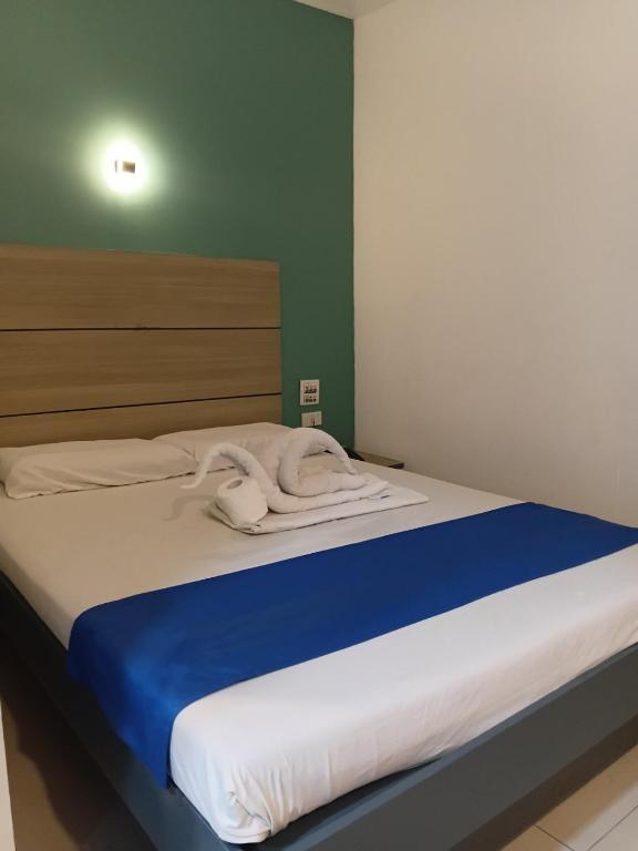 a bed with a blue and white blanket on it at Nice Hotel in Manila