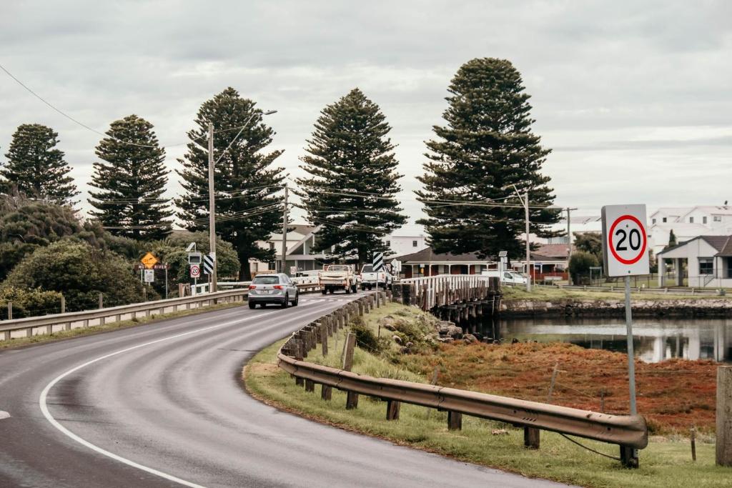 a car is driving down a road with trees at Moyne Views 2 in Port Fairy