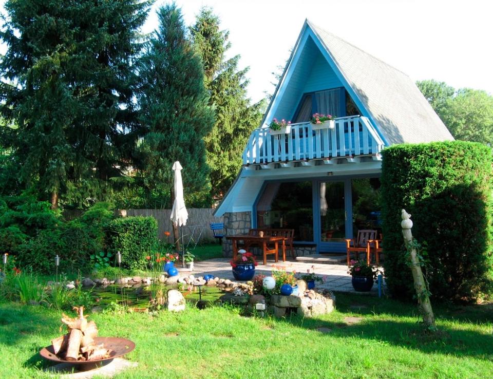 a blue house in a yard with a garden at Ferienhaus mit Pool am See in Malchow