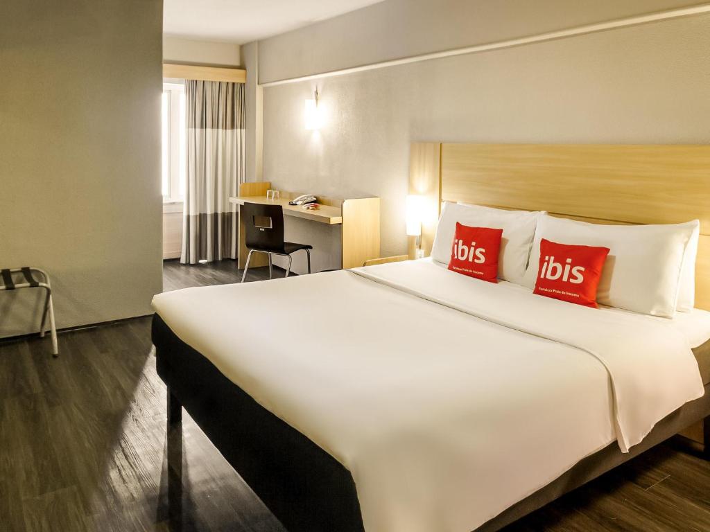 a hotel room with a large bed with red pillows at ibis Fortaleza Praia de Iracema in Fortaleza