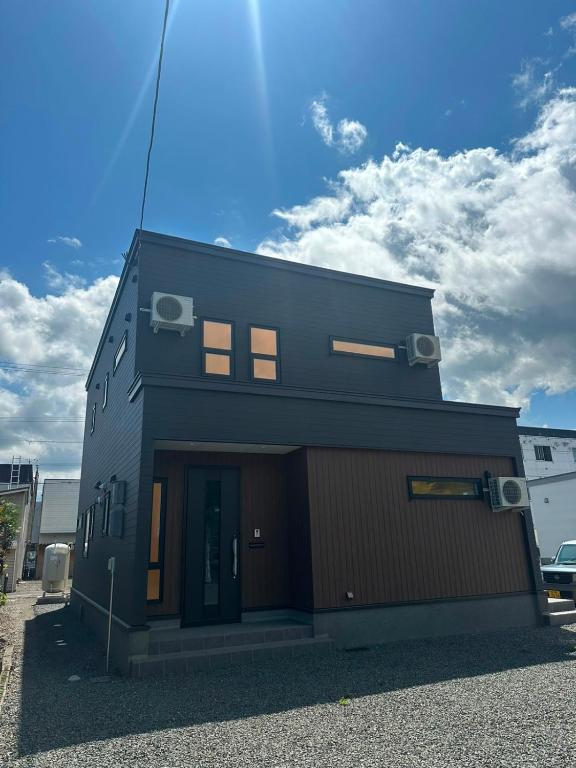 a small black building with a garage at Hotel Ji ホテル時 in Furano