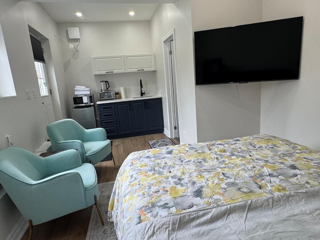 a bedroom with a bed and two chairs and a flat screen tv at Home away from home! in Pickering