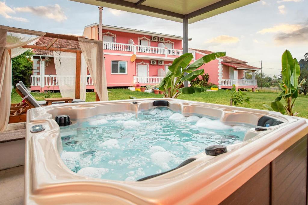 a hot tub on a patio with a house in the background at Riposo Studios & Apartments in Kavos