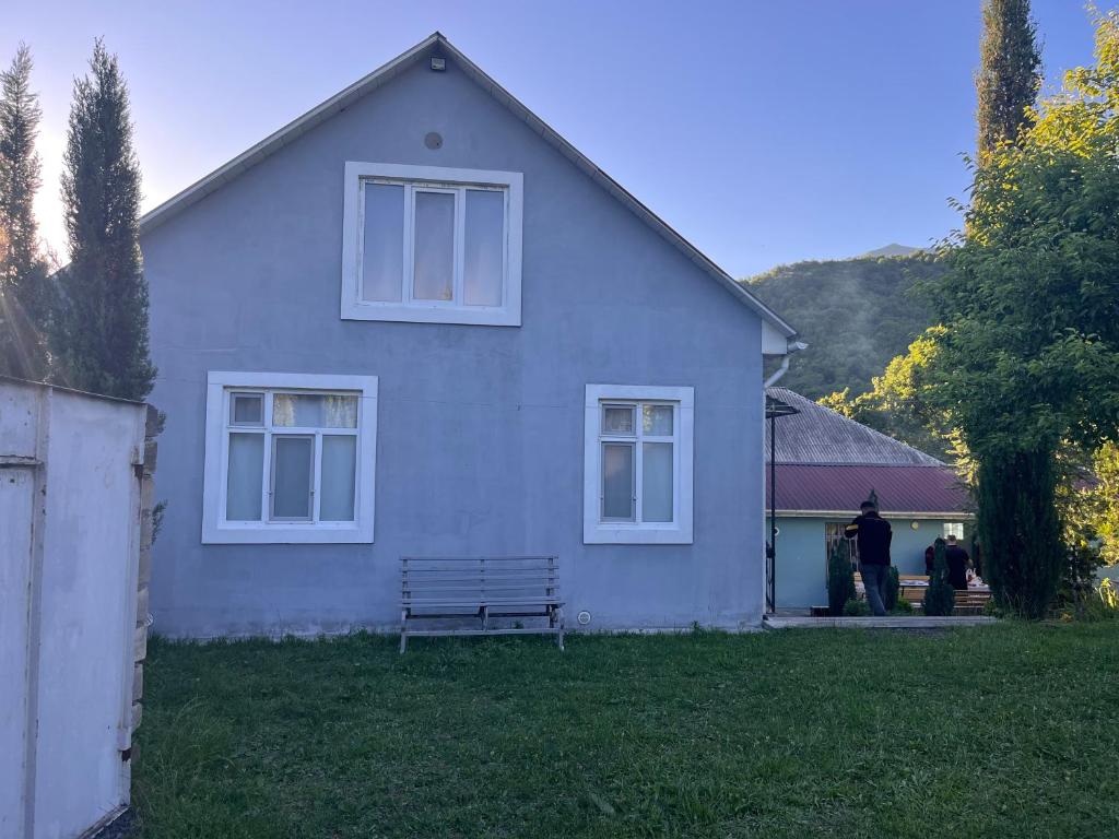 a man standing in front of a white house at Zaqatala-Car riverside cottage in Zaqatala