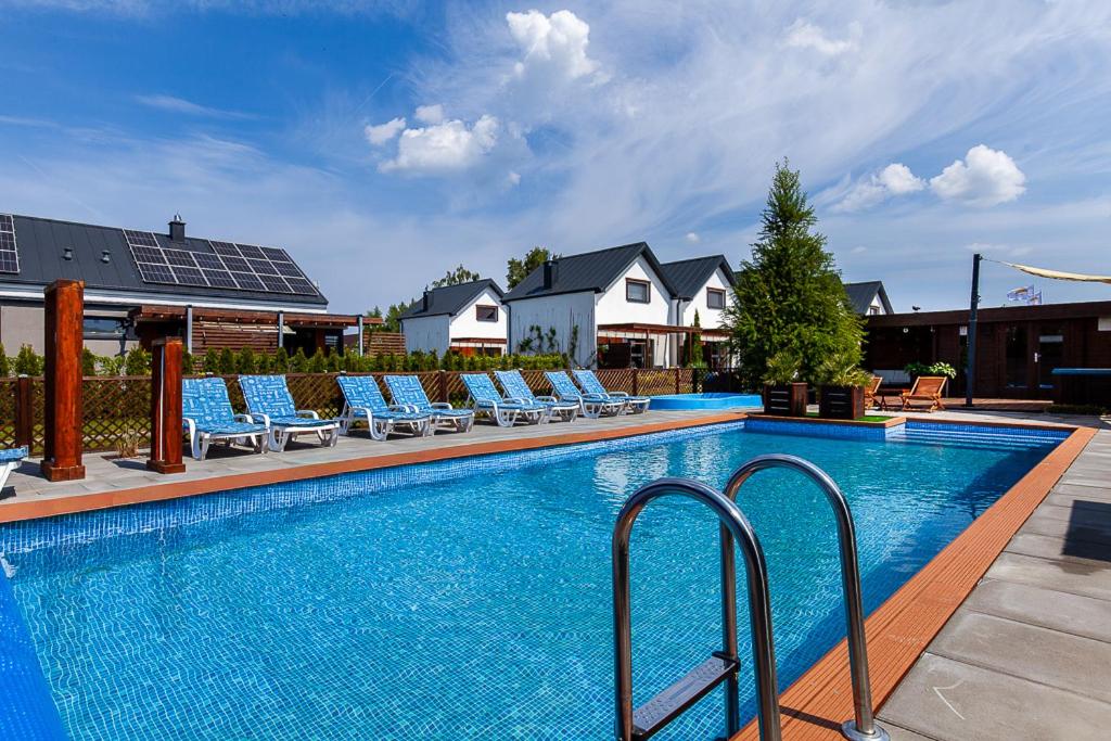 a swimming pool with lounge chairs next to a house at Corden Village in Łeba