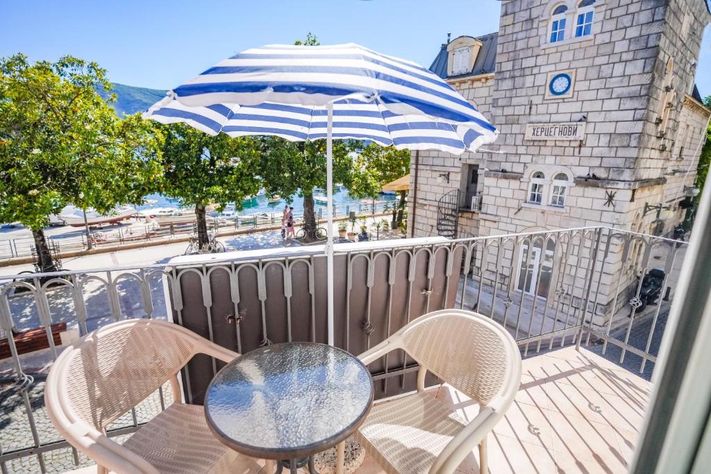 a table and chairs on a balcony with an umbrella at Apartments Astoria HN in Herceg-Novi