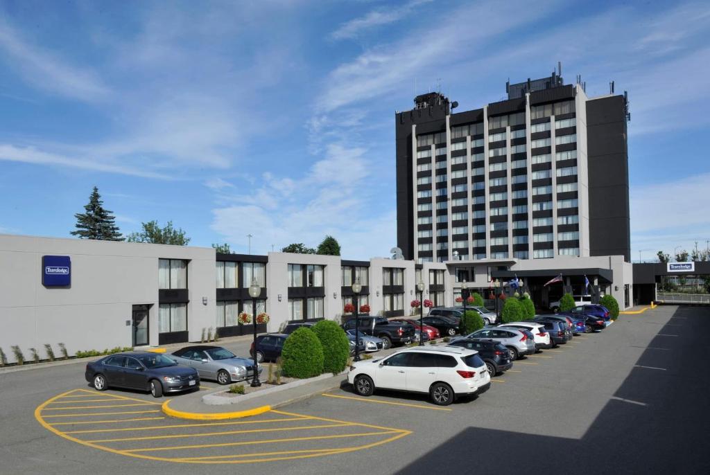 a parking lot with cars parked in front of a building at Travelodge by Wyndham Quebec City Hotel & Convention Centre in Quebec City