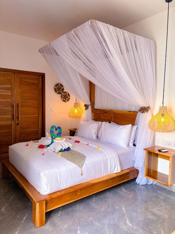 a bedroom with a large white bed with a canopy at Ajolie Villa in Gili Islands