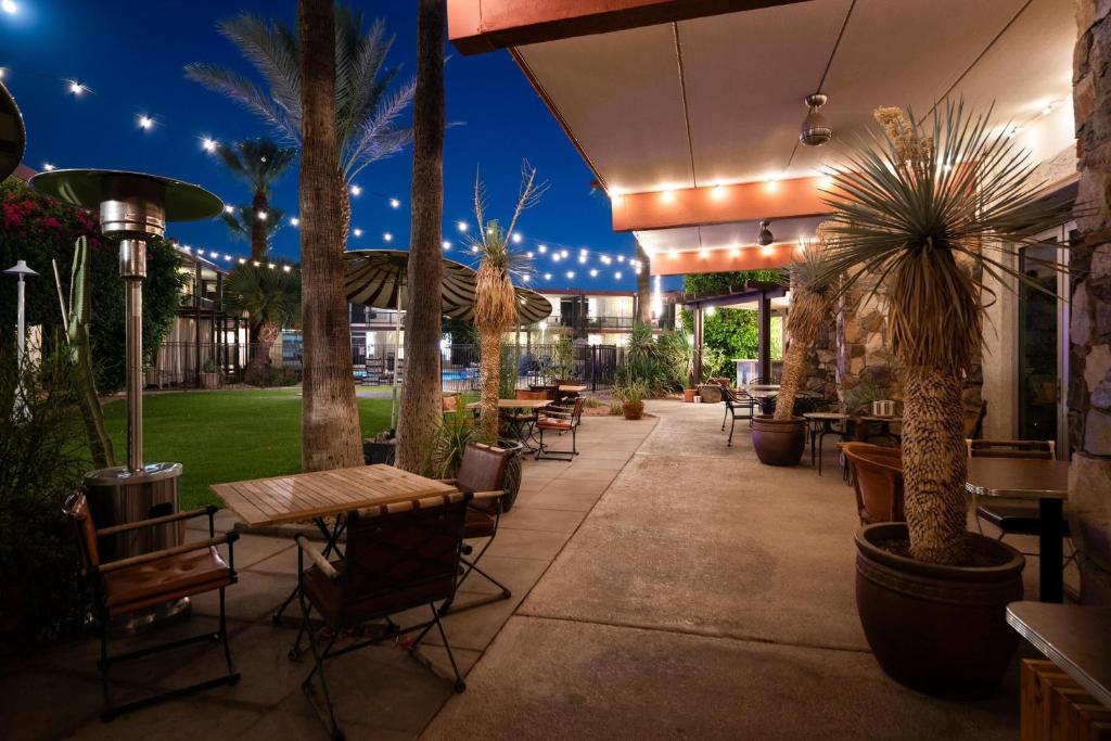 a patio with tables and chairs and palm trees at night at Papago Scottsdale by Reside, Trademark Collection by Wyndham in Scottsdale