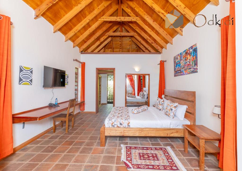 a bedroom with a bed and a desk and a tv at Od Kidi Cottages in Migori