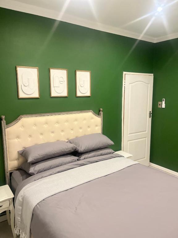 a bedroom with green walls and a large bed at The Residence at 1907 in Thulamahashi
