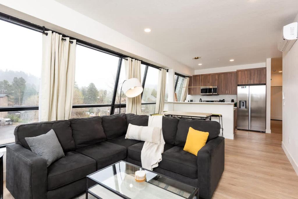 a living room with a black couch and some windows at Modern condo with town and mountain views in Evergreen