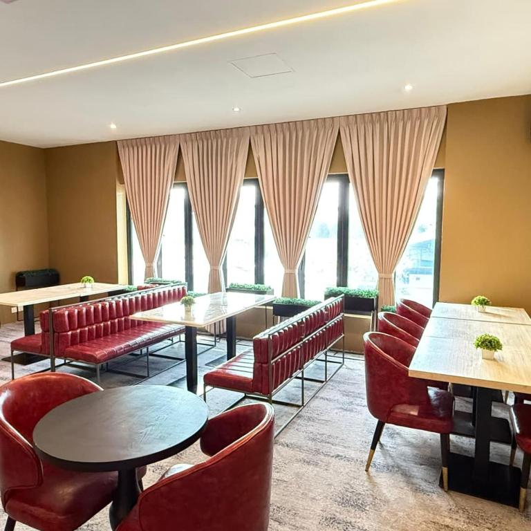 a restaurant with red chairs and tables and windows at Regatta at Kozi Square Kuching in Kuching