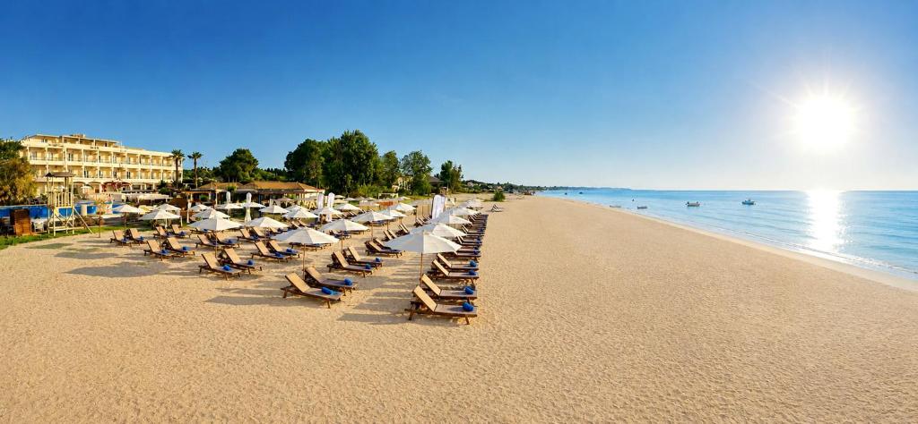 a row of beach chairs and umbrellas on a beach at Cavomarina Beach- Adults Only in Kavos