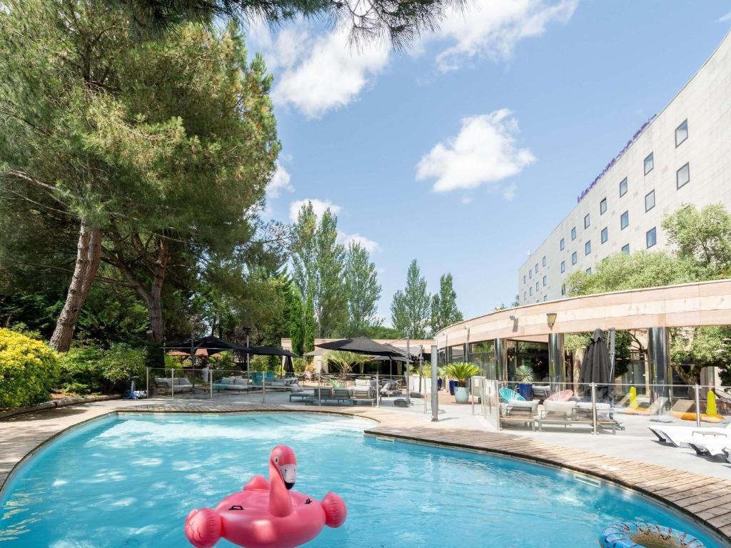two pink flamingos in a swimming pool at a hotel at Mercure Bordeaux Aéroport in Mérignac
