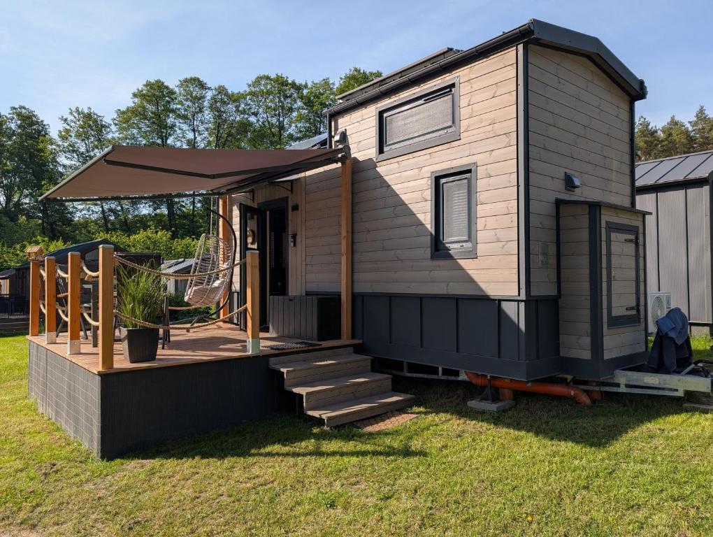 a tiny house with a porch and a deck at Tiny House WaldSEEle in Stuer