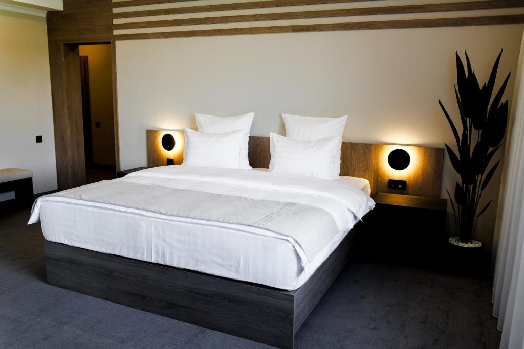 a bedroom with a large bed with white sheets and pillows at Altay Resort in Shchūchīnsk