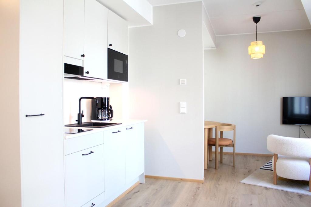 a kitchen with white cabinets and a white chair at Spot Apartments Airport Premium in Vantaa