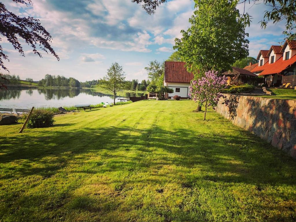 a large yard with a lake and a house at Dom Nowe Krzywe in Nowe Krzywe