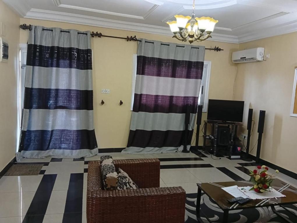 a living room with curtains and a couch and a table at Palace Ndogbong Bifaga in Bassa