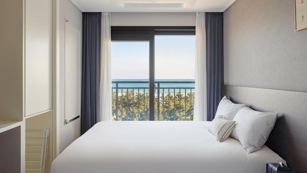 a bedroom with a large bed with a large window at Urbanstay Sokcho Beach AB in Sokcho