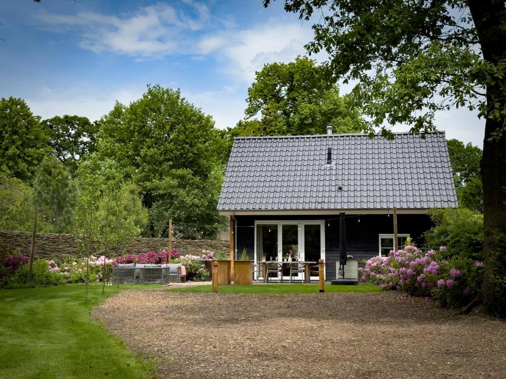 a small house with a garden and flowers at Heemhoeve Lodge in Emst