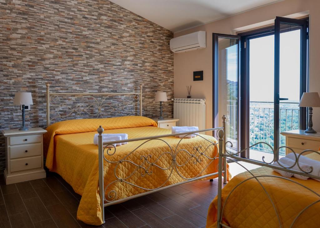 a bedroom with two beds and a brick wall at B&B MALVETUM in Malvito