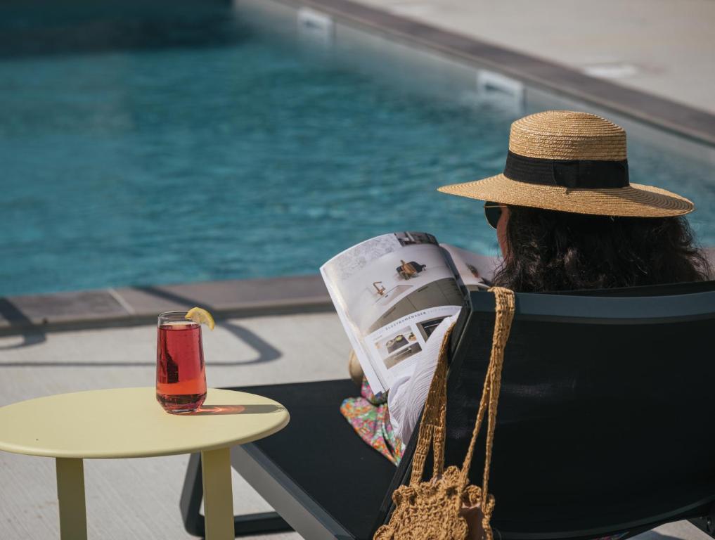 a woman sitting in a chair reading a magazine at Kyriad Chateauroux Nord - Aéroport in Déols
