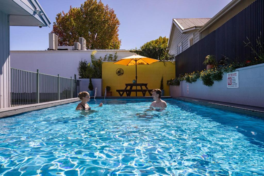 two children are swimming in a swimming pool at Kowhai Motel Rotorua in Rotorua