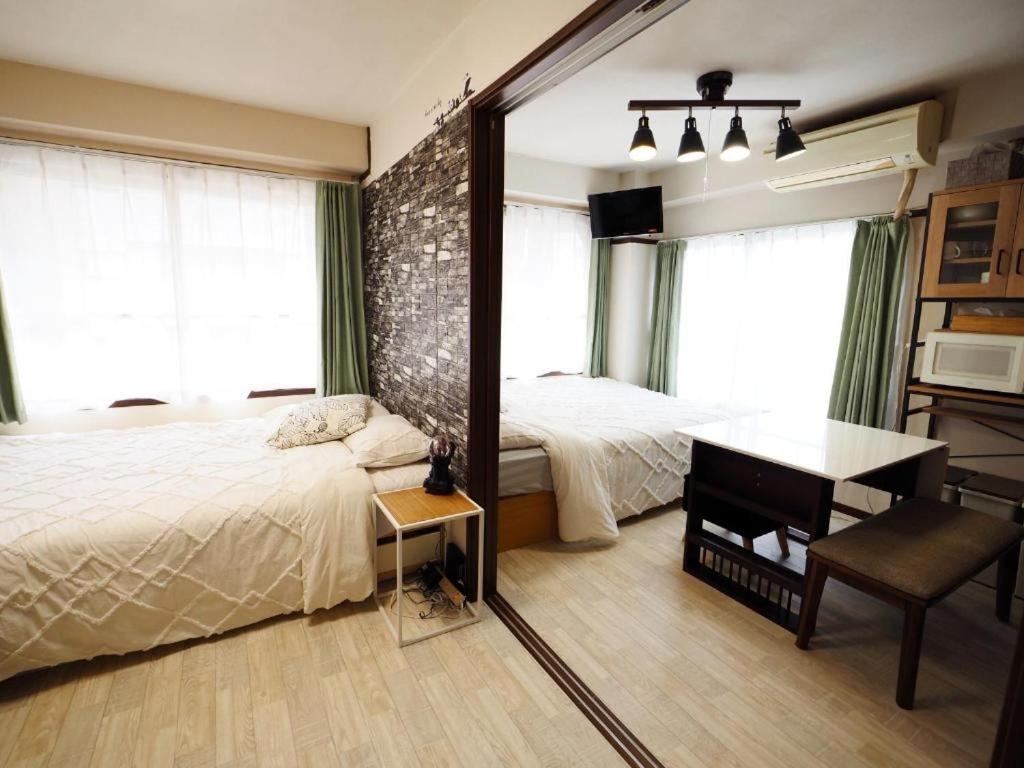 a bedroom with two beds and a desk and a mirror at Miyabi Stay Tokyo in Kamatachō