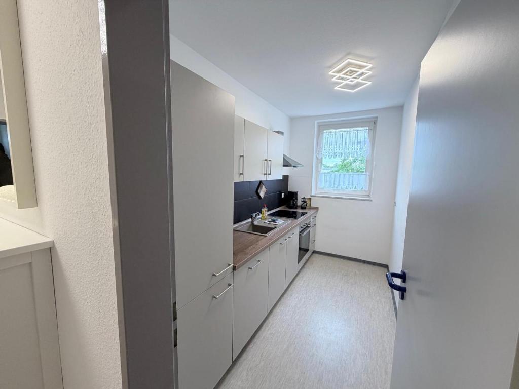 a kitchen with white cabinets and a sink and a window at Gemütliche Ferienwohung in Neubrandenburg
