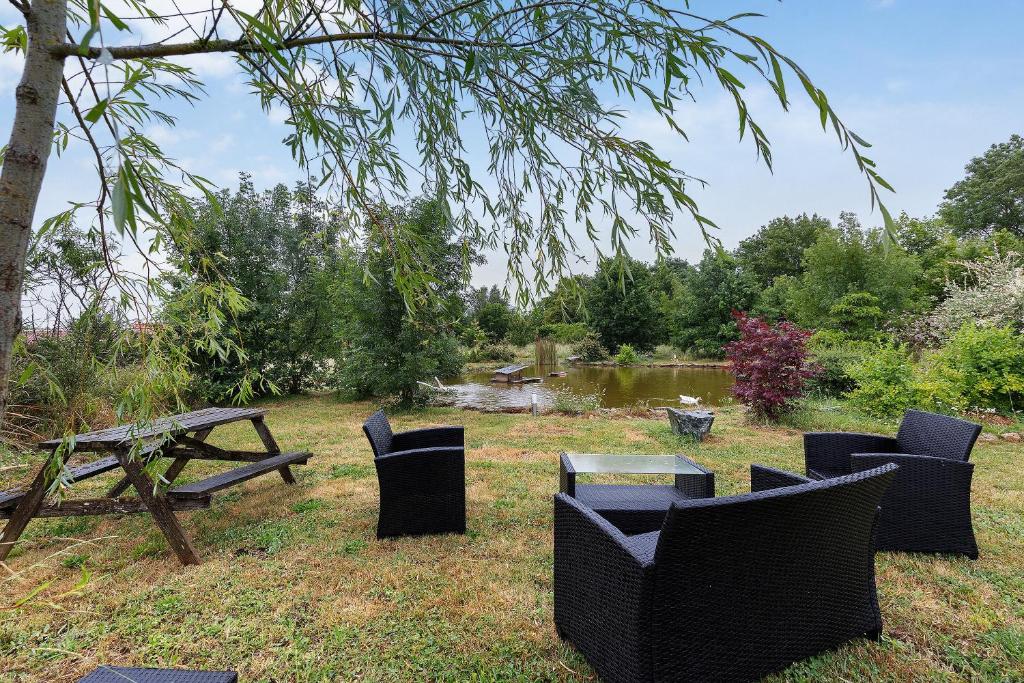 a picnic table and chairs next to a picnic table and a lake at Gîtes Du Logis De Bourseguin in Bourneau